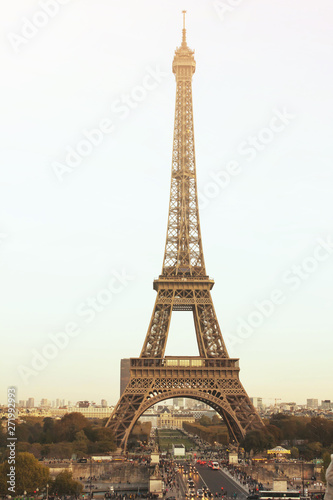 Paris/France - 10 23 2018: The Eiffel Tower in the day bright sun lights. The road under the huge tower, red lights of cars. Famous architectural monument and construction, symbol of France and Paris. © Daniil