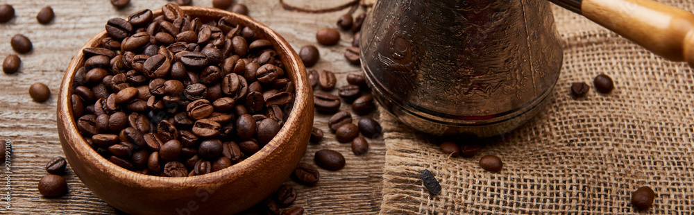 Fototapeta premium panoramic shot of cezve near coffee beans in bowl on wooden background