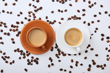 top view of coffee in white and brown cups on saucers near scattered roasted beans