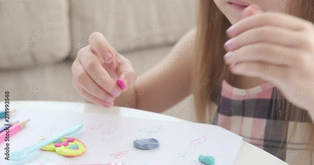 Little girl playing with plasticine on drawing paper Little girl playing with plasticine on drawing paper