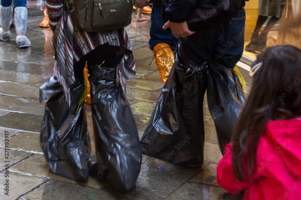 Tourists during a flood in the center of Venice go with their feet wrapped in large black garbage bags. Galoshes, boot covers from trash bags. Savvy and quick thinking. Protection against water.