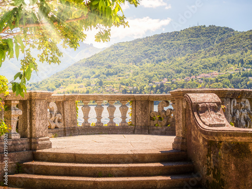 Italian stone balustrade illuminated by sun rays and water in the background photo