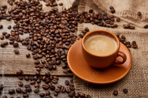 coffee beans near cup of coffee on wooden background