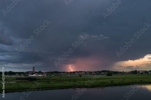 Lightning strikes down to earth from an evening thunderstorm over the dutch river landscape