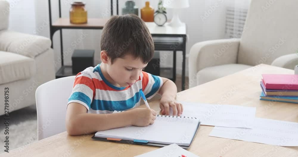 Boy rewriting information from paper in copy book Boy rewriting information from paper in copy book