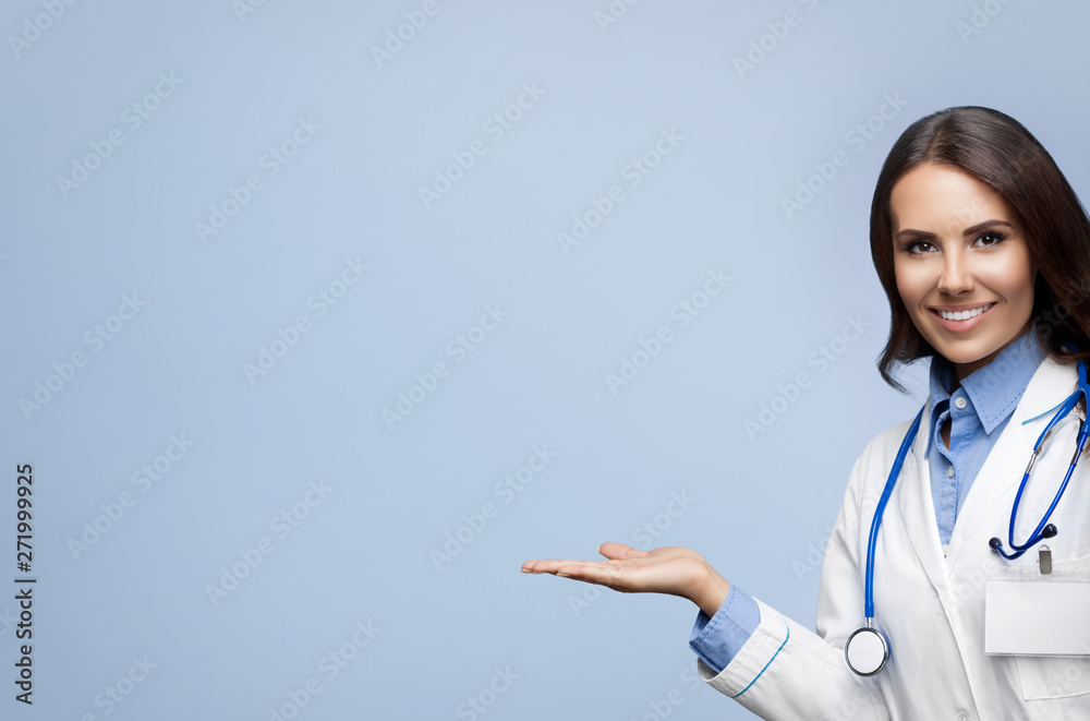 Female doctor showing something or blank copy space for slogan or sign text, isolated against grey background Female doctor showing something or blank copy space for slogan or sign text, isolated against grey background