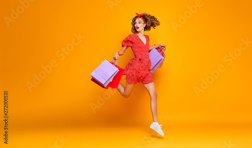 concept of shopping purchases and sales of happy young girl with packages  on yellow background photo