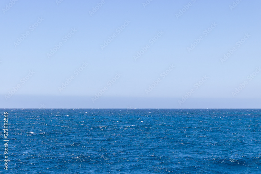 Seascape with sea horizon and almost clear deep blue sky