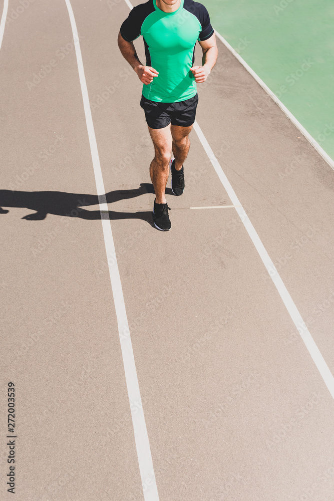 cropped view of sportsman in sportswear running at stadium cropped view of sportsman in sportswear running at stadium