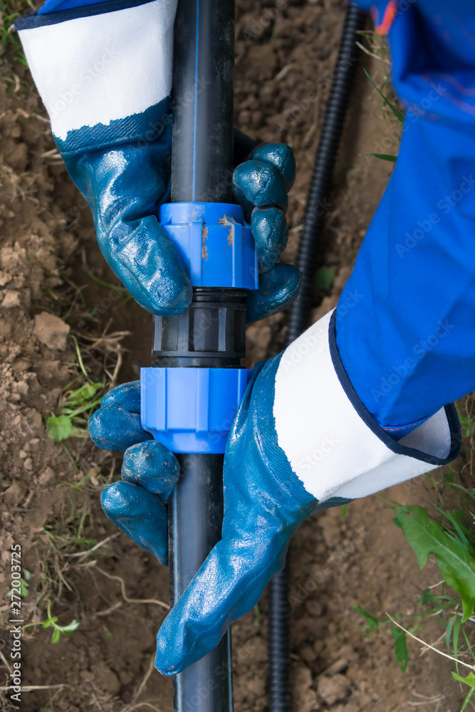 hands in rubber gloves connect thick long pipes for water hands in rubber gloves connect thick long pipes for water