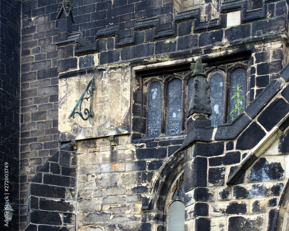 a full frame close up of ancient stonework stained glass windows and a sundial on the medieval