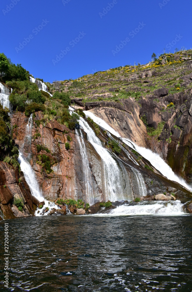 Colorful waterfall with rocks and vegetation. Ezaro, Spain.