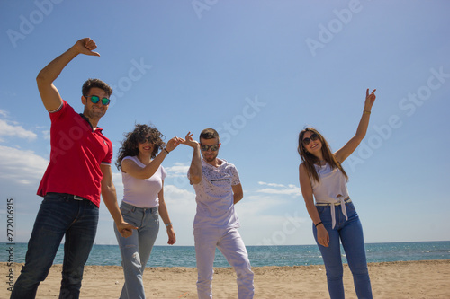 Group of friends celebrate Summer holiday at beach dancing and enjoying this happy moment