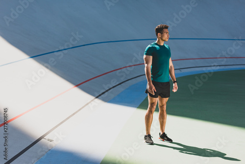 mixed race sportsman standing in light place at stadium near running track