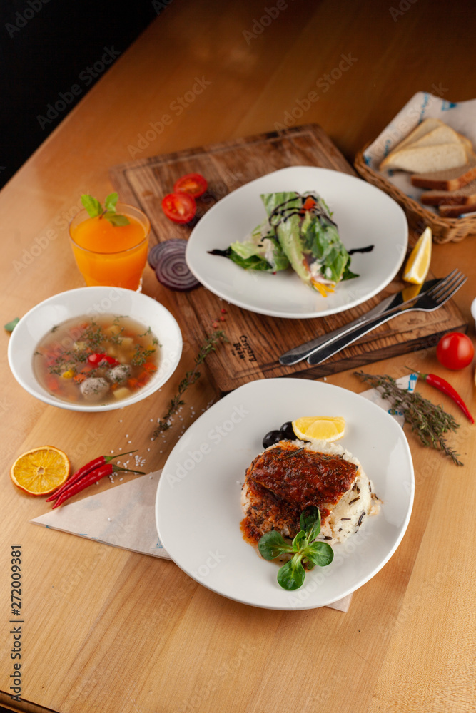 Set lunch menu in a restaurant: fish with steamed rice, light vegetable soup with meatballs and vegetarian spring roll