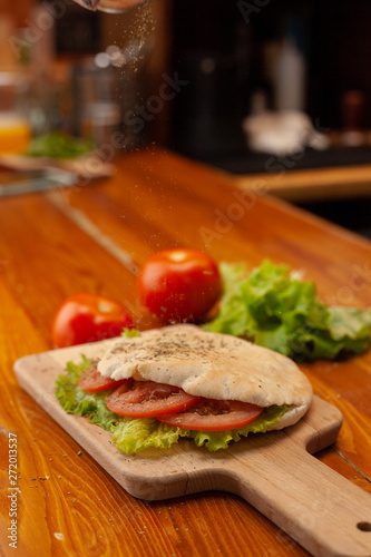 Mouth-watering vegetarian pita  stuffed with hummus  greens  tomatoes and herbs  served on a rustic wooden table