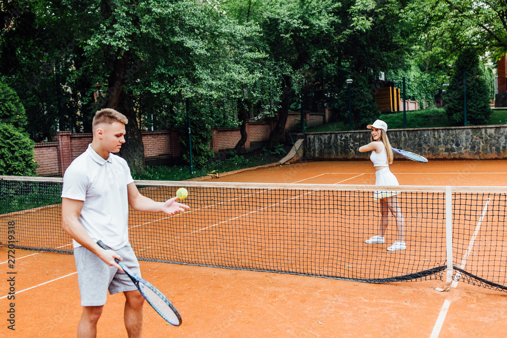 Man, tennis teacher, showing woman how to play the racket sport outdoors. Sporty life..