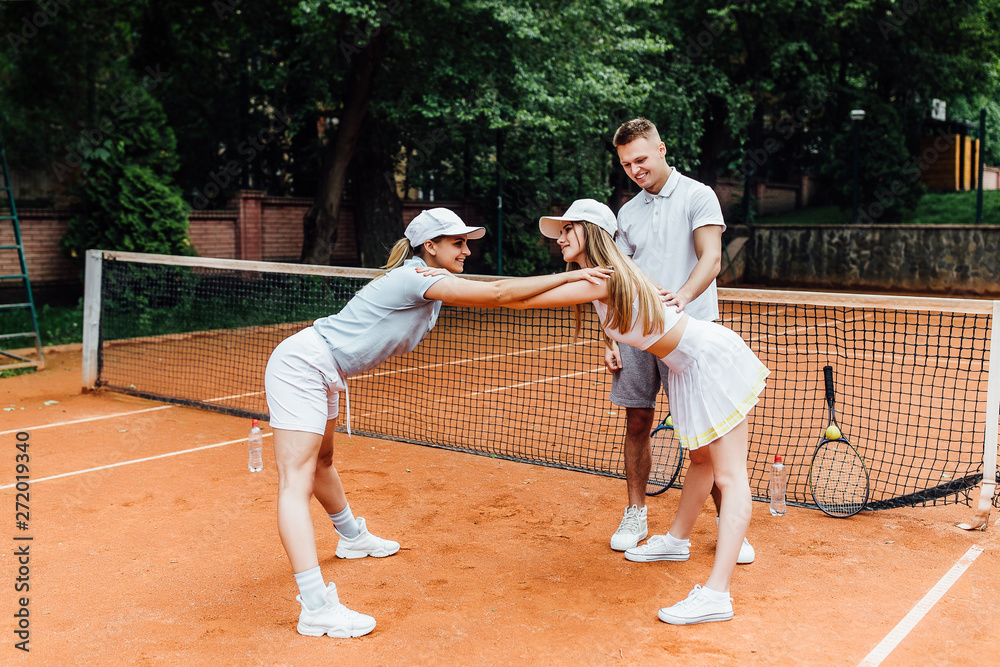 Attractive trainer help stretch to two  female tennis player bending and touching their competition.