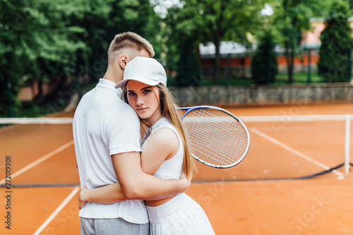 Happy couple hugging after tennis playing,training outdoors together..