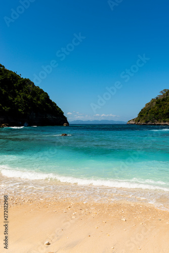 View of tropical beach  sea rocks and turquoise ocean  blue sky. Atuh Beach  Nusa Penida  Indonesia.