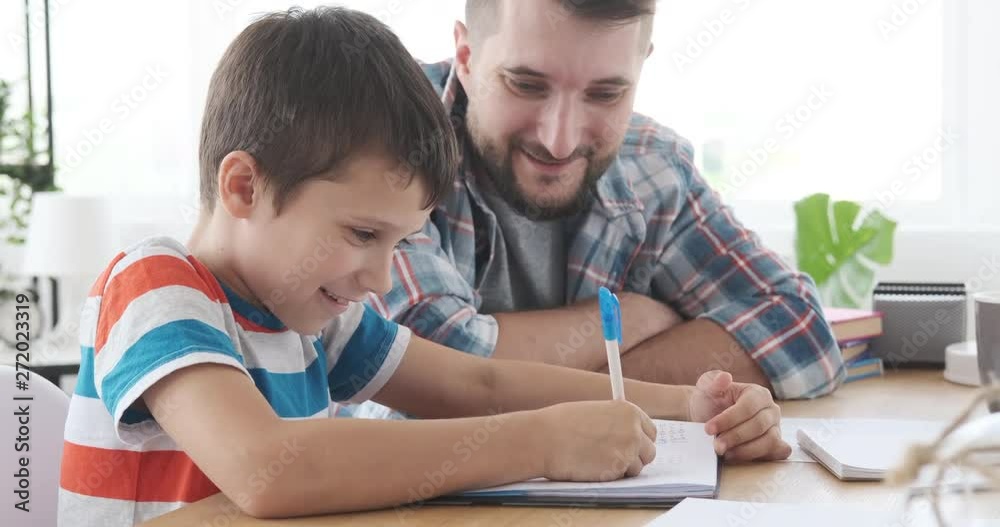 Father and son having fun doing homework together at home Father and son having fun doing homework together at home