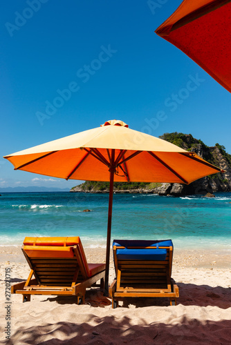 Pair of sun loungers and a beach umbrella on a deserted beach. Perfect vacation concept