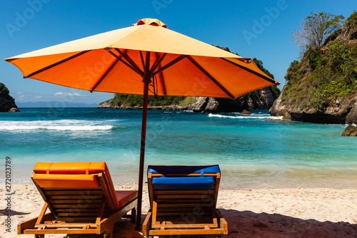 Pair of sun loungers and a beach umbrella on a deserted beach. Perfect vacation concept