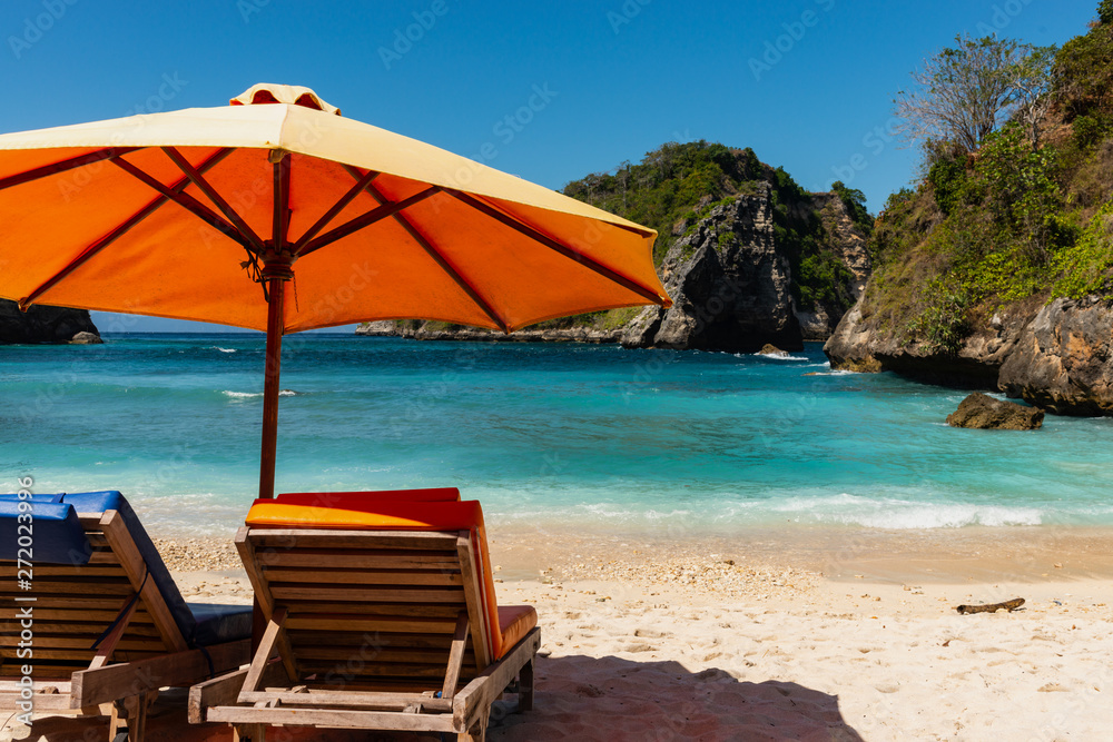 Pair of sun loungers and a beach umbrella on a deserted beach. Perfect vacation concept