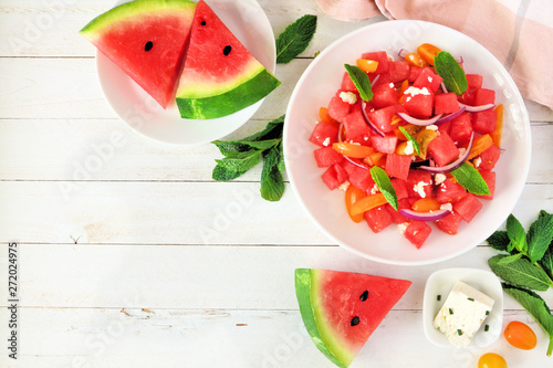 Watermelon and tomato salad with feta cheese. Top view, corner border on a white wood background with copy space.