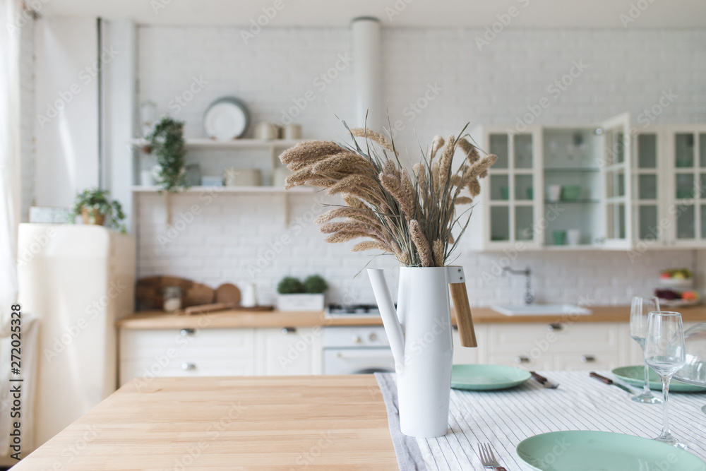 A vase with dry flowers on a table. Scandinavian classic kitchen with  wooden and white details, minimalistic interior design. Real photo.Cosy  home. foto de Stock | Adobe Stock