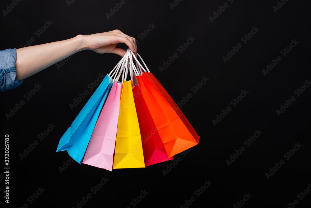 Woman hand holding colorful shopping bags over dark background