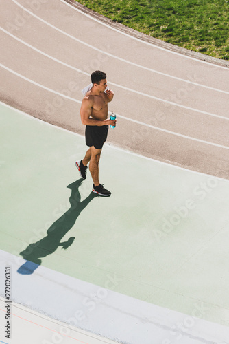 overhead view of mixed race sportsman holding towel and sport bottle at stadium