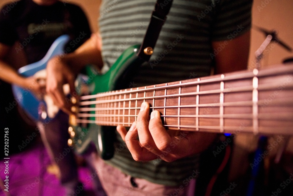 Guitarist playing the notes of a bass during a rehearsal, close-up.