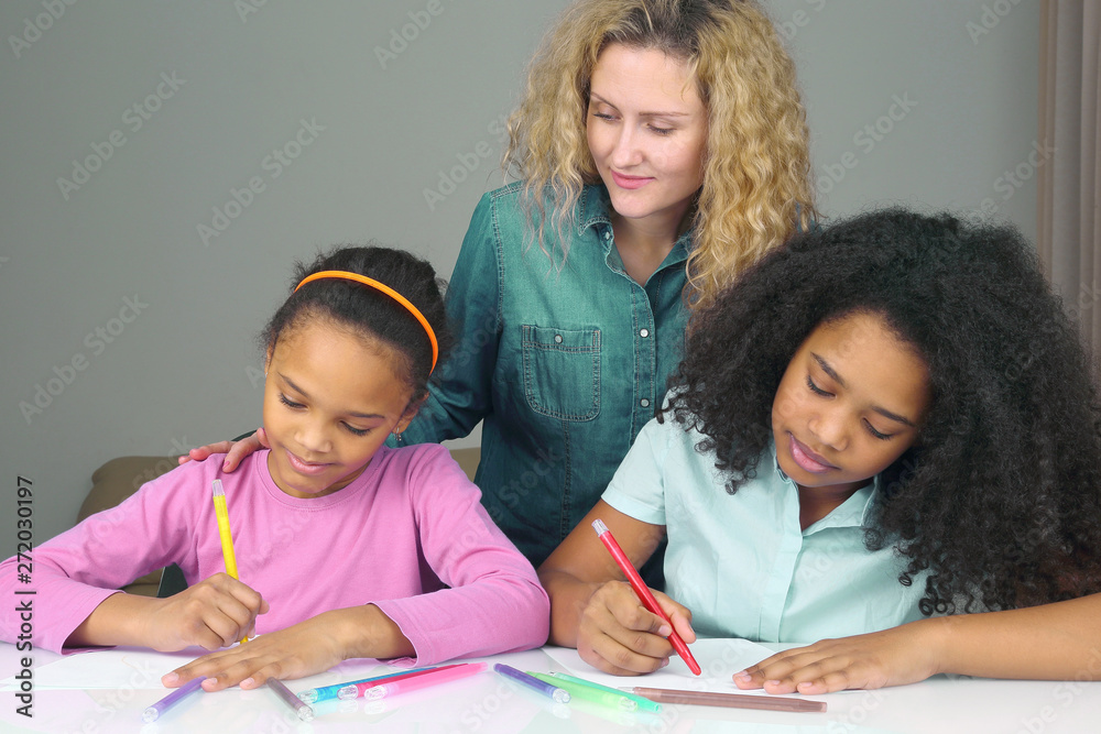 mom watches as her daughter drawing with crayons. mom watches as her daughter drawing with crayons.
