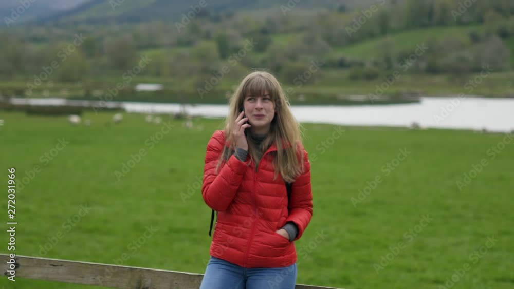 Young woman takes a phone call while standing in a typical Irish scenery - travel photography Young woman takes a phone call while standing in a typical Irish scenery - travel photography
