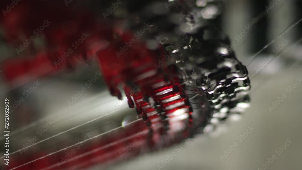 Cotton threads travel through gears of an automated textile knitting machinery in textile factory in China