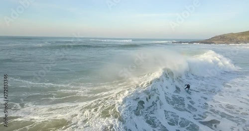 Drone aerial top down view / perspective of a Surfer catching a large wave while trying to race ahead of the crashing white water to stay on his surfboard photo