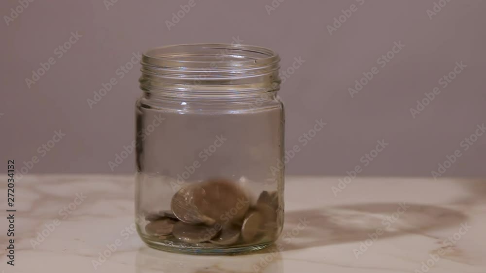 Continuous stream of coins dropping into a glass jar. Continuous stream of coins dropping into a glass jar.