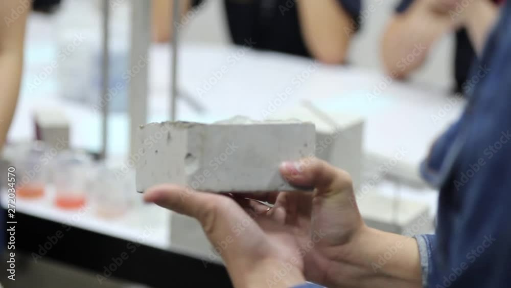 Scientist applying purple liquid on a concrete block that cracked from a compression test. Scientist applying purple liquid on a concrete block that cracked from a compression test.