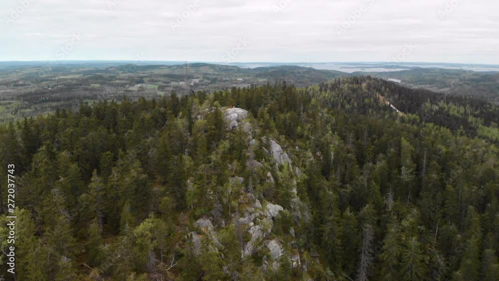 Aerial, rising, drone shot, tilting down towards Ukko-Koli peak and lake Pielinen, surrounded by spring color woods, on a partly sunny day, in Koli national park, Pohjois-Karjala, Finland Aerial, rising, drone shot, tilting down towards Ukko-Koli peak and lake Pielinen, surrounded by spring color woods, on a partly sunny day, in Koli national park, Pohjois-Karjala, Finland