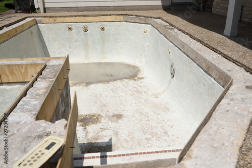 Empty swimming pool drained for remodel with new concrete and wooden forms for tile and coping
