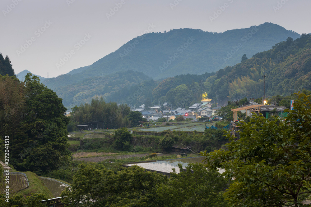 Rice fields and buildings in small Japanese mountain town at dusk