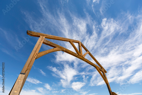 Low angle view of wooden gateway entrance to ranch against a blue sky