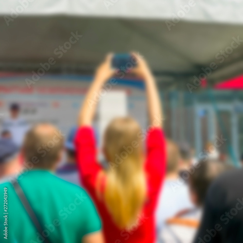 Blurred Girl in Red Dress Raised Hands Recording the Event with Smartphone.