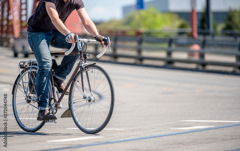 Cyclist in jeans prefer an active lifestyle and rushes on bicycle on city bridges