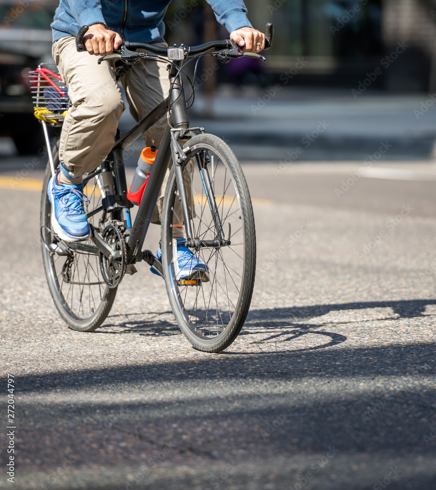 Cyclist rides bicycle with basket at the back along city street Cyclist rides bicycle with basket at the back along city street