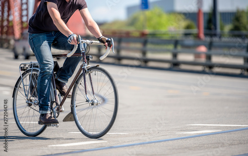 Cyclist in jeans prefer an active lifestyle and rushes on bicycle on city bridges © vit