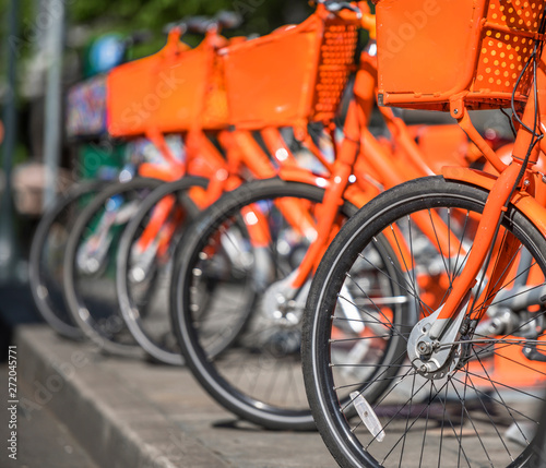 Orange bikes for public rentals stand in line waiting for cyclists