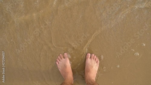 Slow motion, waves washing man feet