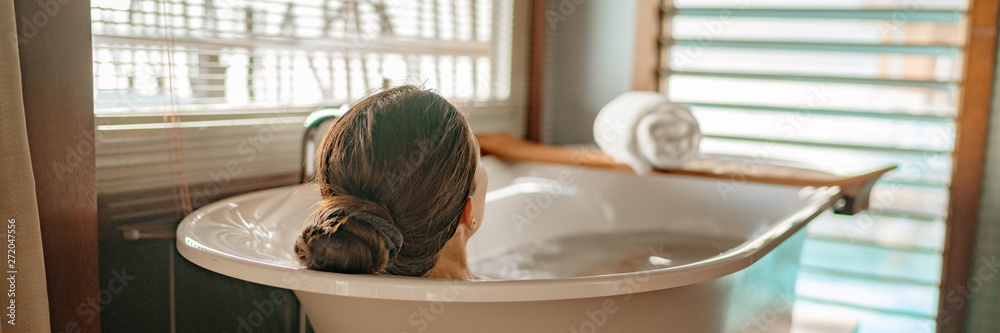 Luxury bath woman relaxing in hot bathtub in hotel resort suite room enjoying pampering spa moment lifestyle banner panorama. - obrazy, fototapety, plakaty 